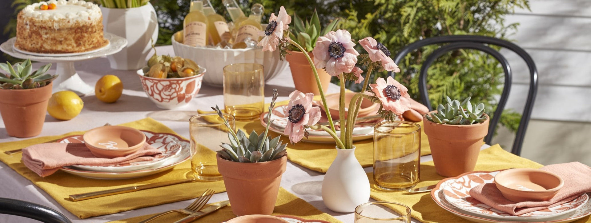 An elegant outdoor table set with flowers and cake.