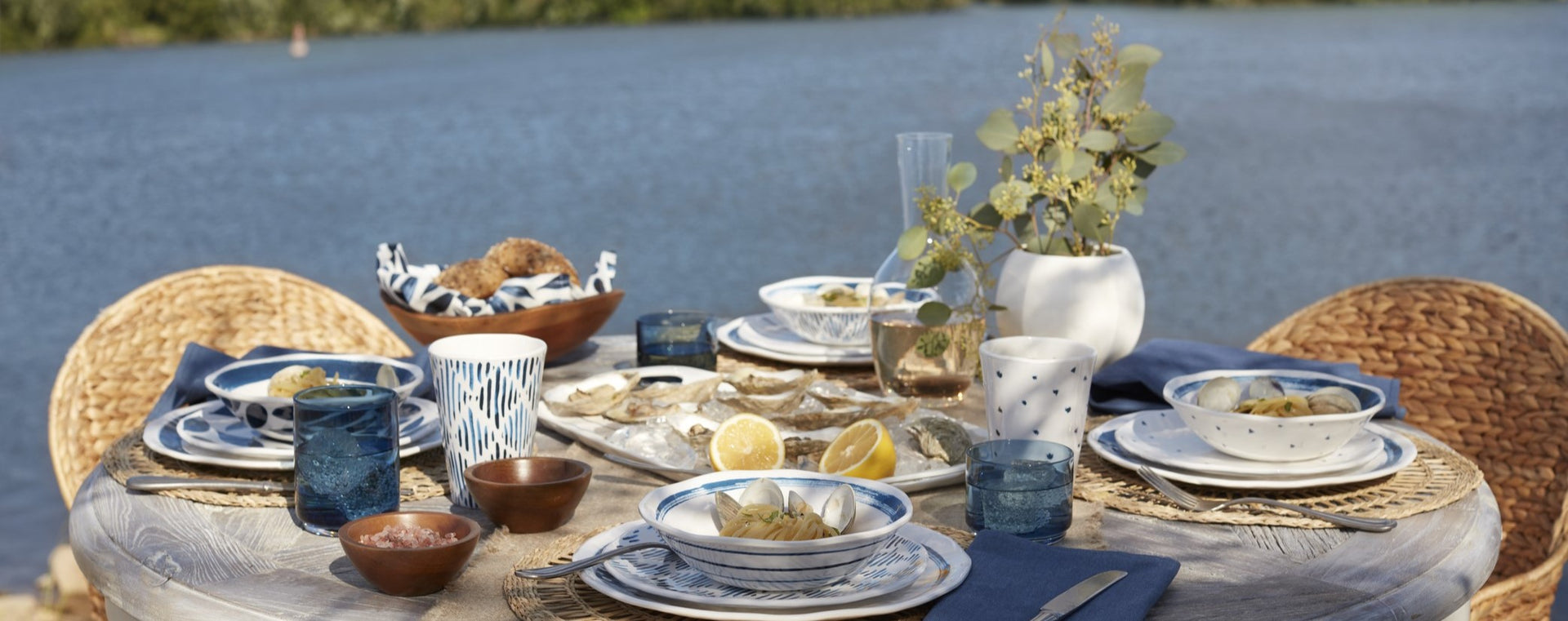 table set with dinnerware in front of water