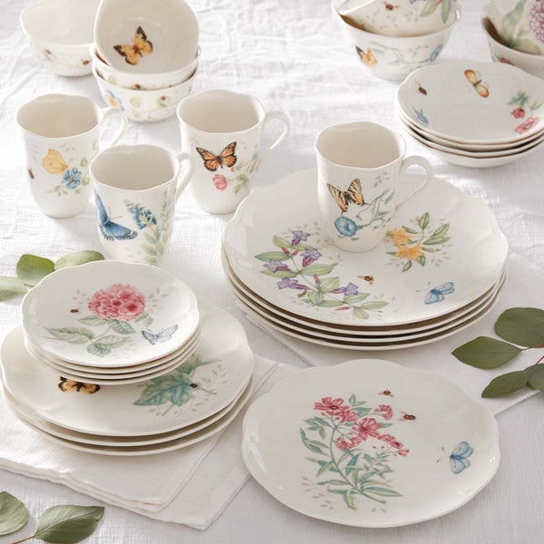 Butterfly Meadow plates, mugs, and bowls stacked on a table with a white tablecloth