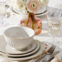 French Perle Groove dinnerware on a table with florals in a pink vase and clear glassware