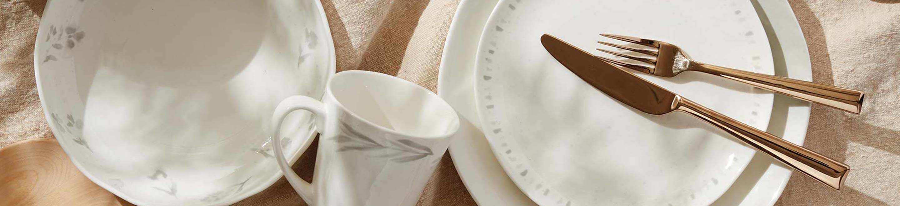 overhead shot of white dinnerware and gold flatware