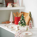 Decorative Christmas kitchen scene with mugs, plates, and a tree on a countertop.