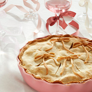 Pie with decorative crust in a pink dish on a white background