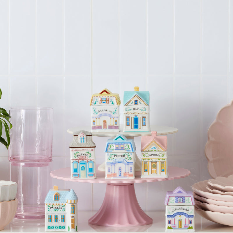 Decorative house-shaped boxes on a pink stand with a white background