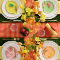 Colorful table setting with floral centerpieces, colorful plates, and a checkered tablecloth.