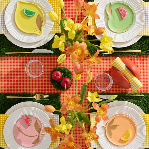 Colorful table setting with floral centerpieces, colorful plates, and a checkered tablecloth.