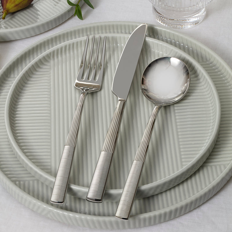 Silver cutlery set on a textured green plate with a light background