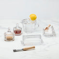 Clear glass kitchenware items including a juicer, bowls, and a citrus reamer on a white background.