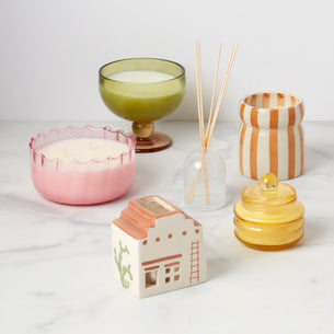 Collection of decorative candles and diffusers on a white surface