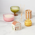 Collection of decorative candles and diffusers on a white surface